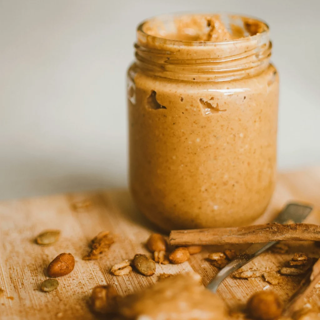 Ein Glas mit Erdnussbutter steht auf einem Holztisch